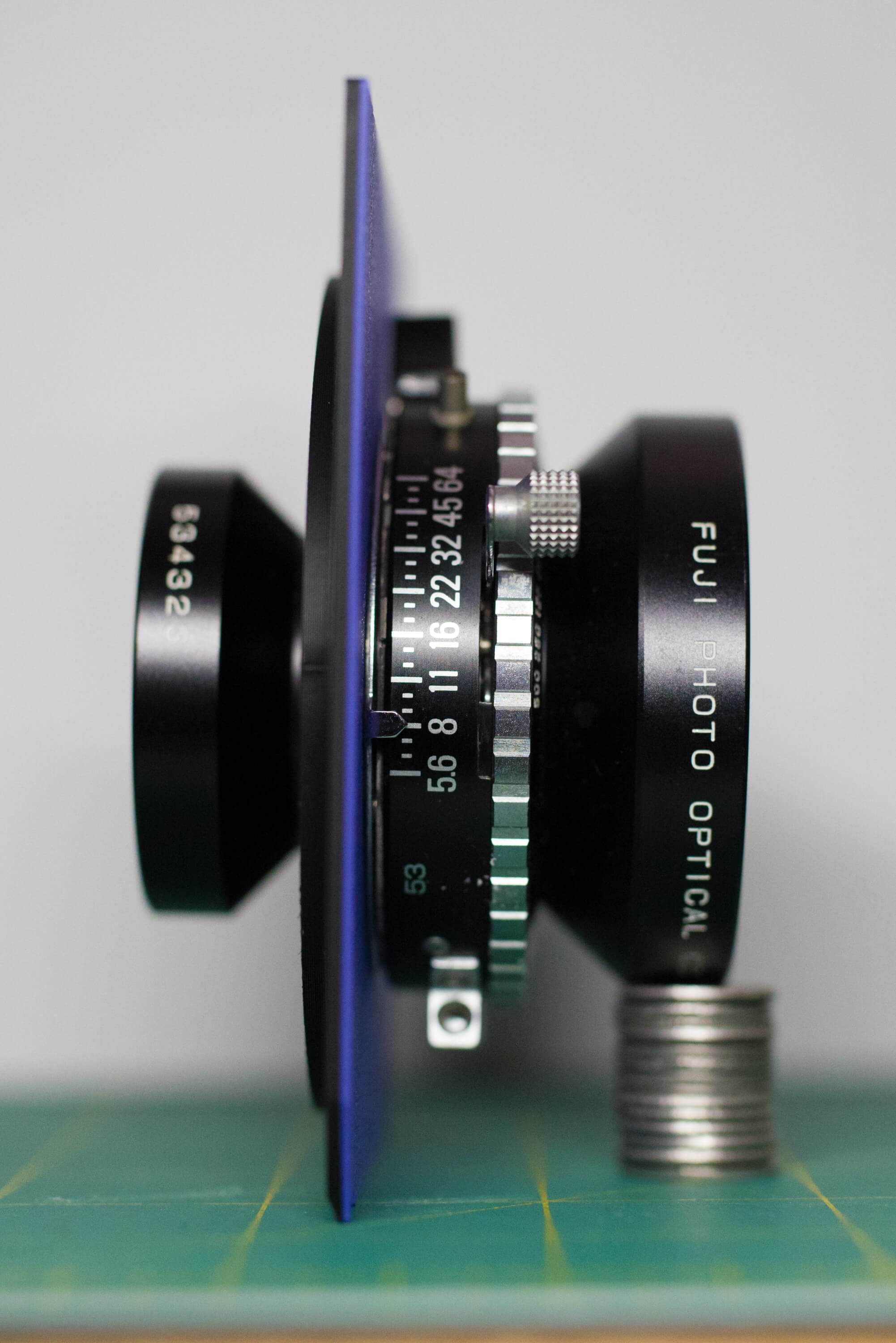 Fuji 150mm lens attached to a Copal 0 lens board, profile view shows (from right to left) the front element, shutter, lens board, retaining ring, and rear glass